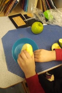 A child putting half of an apple inside a blue bowl