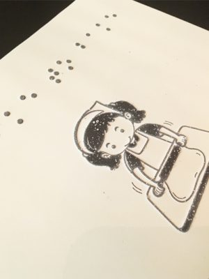 Braille book with the picture of a girl rolling out dough for baking